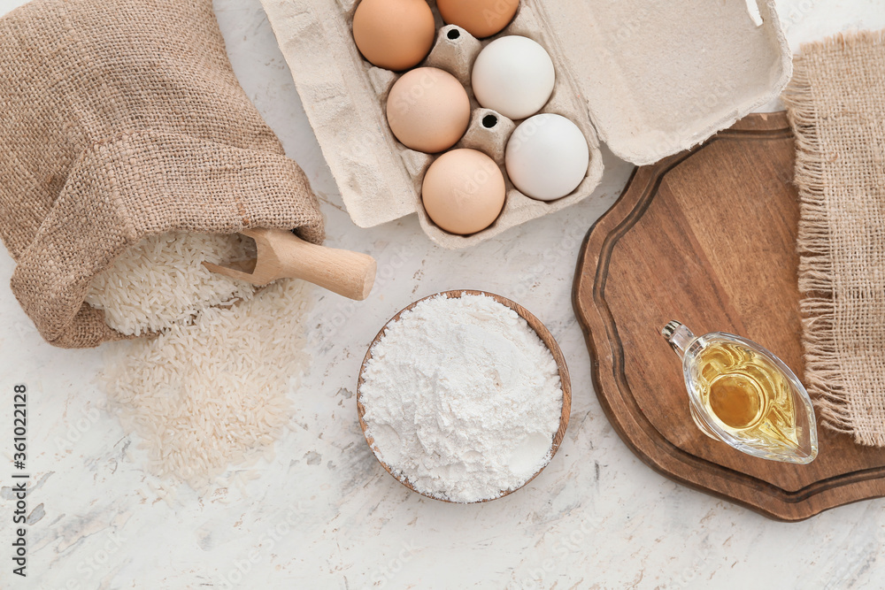 Plate with rice flour and products on white table