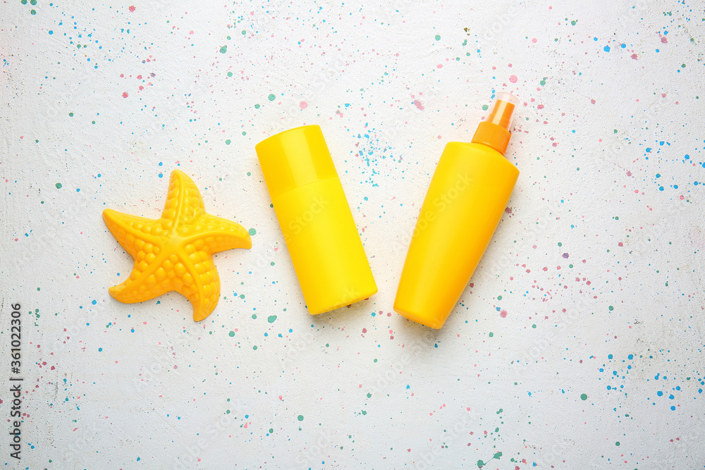 Sunscreen cream with beach sand toy on white background