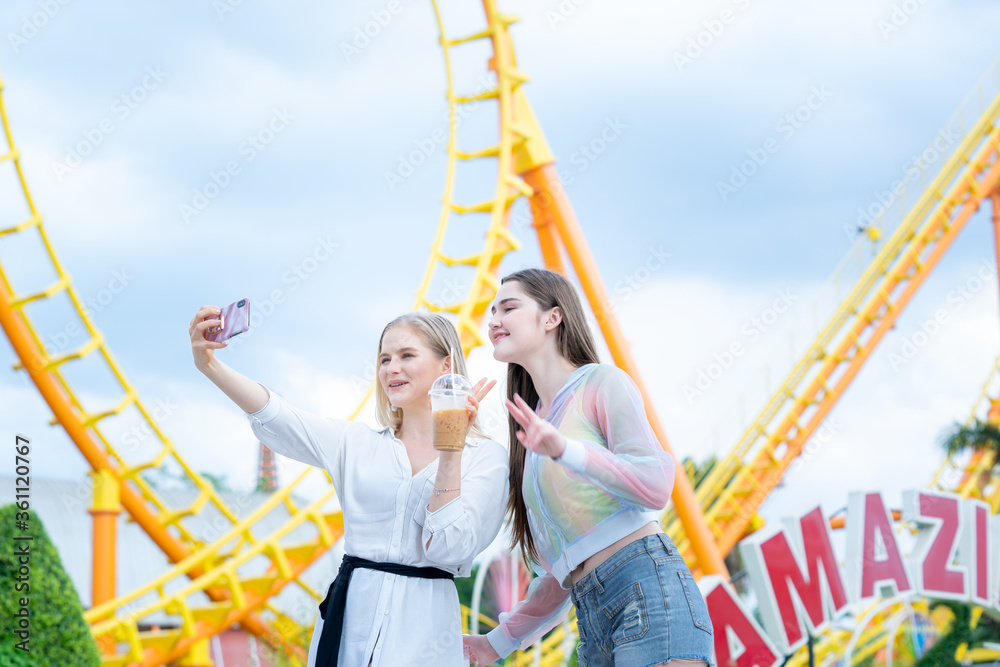 Two cheerful teenage friends taking selfie at the amusement park.