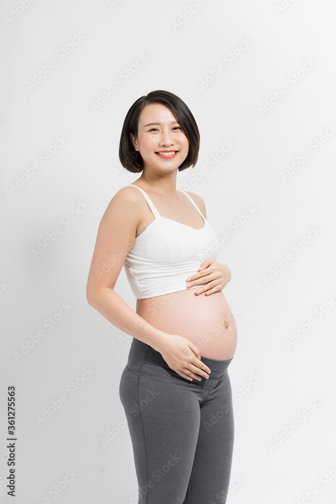 Beautiful pregnant woman touching her belly with hands on a white background.