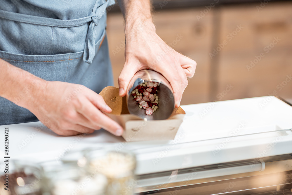 Seller mixing different ice cream toppings for sprinkling on the chocolate ice cream at the shop, cl