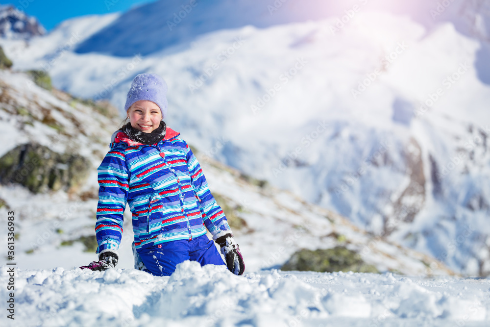 Happy girls with big smile portrait sit in the snow during walk in the mountain in winter clothes