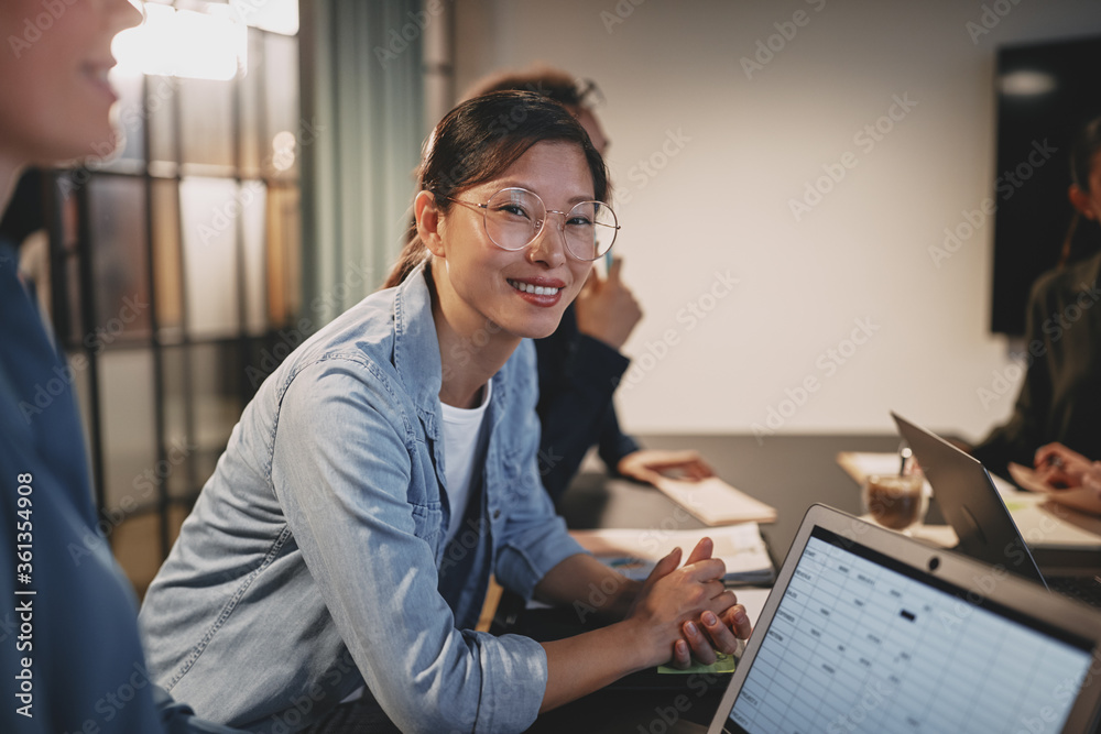 微笑的亚洲女商人与同事坐在办公室