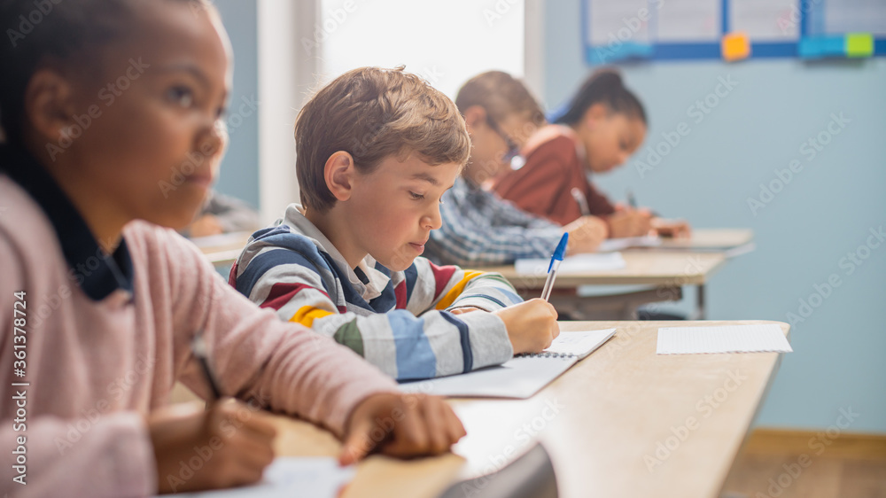 In Elementary School Classroom Brilliant Black Girl Writes in Exercise Notebook, Taking Test and Wri