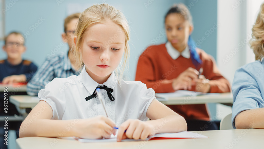 在小学课堂上：一个聪明可爱的高加索女孩的肖像写在练习笔记中