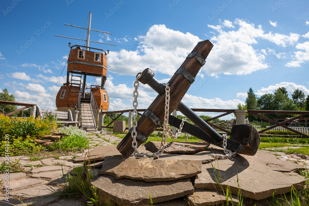 Large anchor as part of the exterior design. Background landscape view with decorative sailboat.  Cl