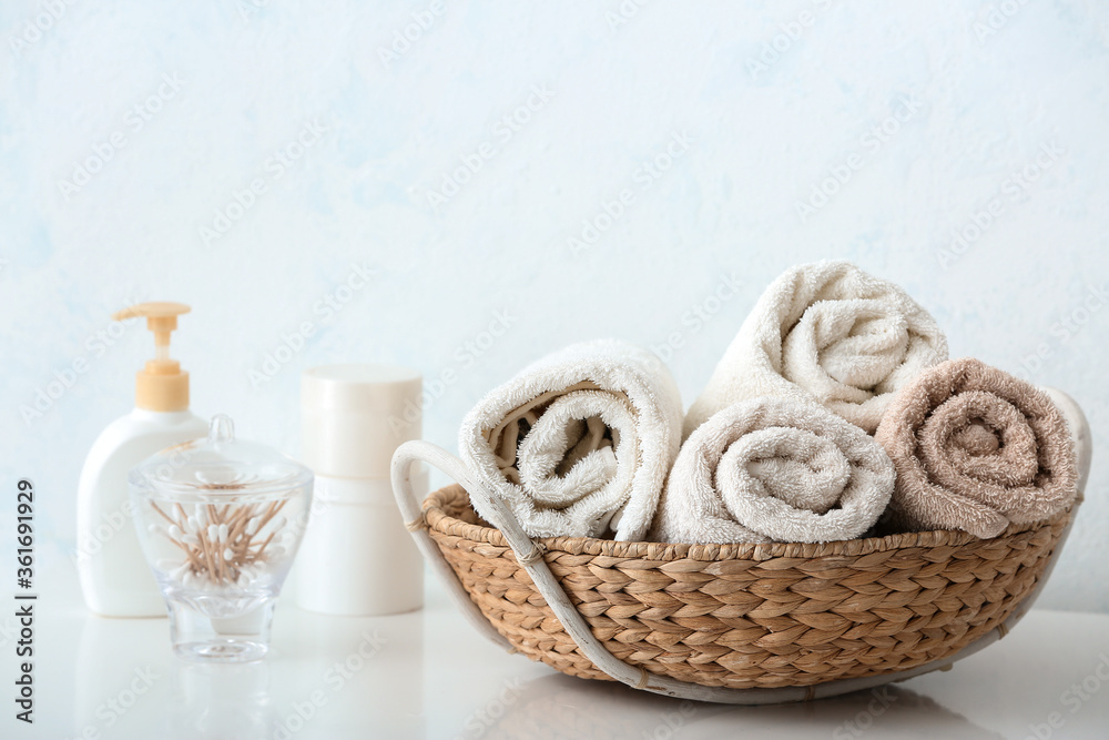 Basket with cotton towels on table in bathroom