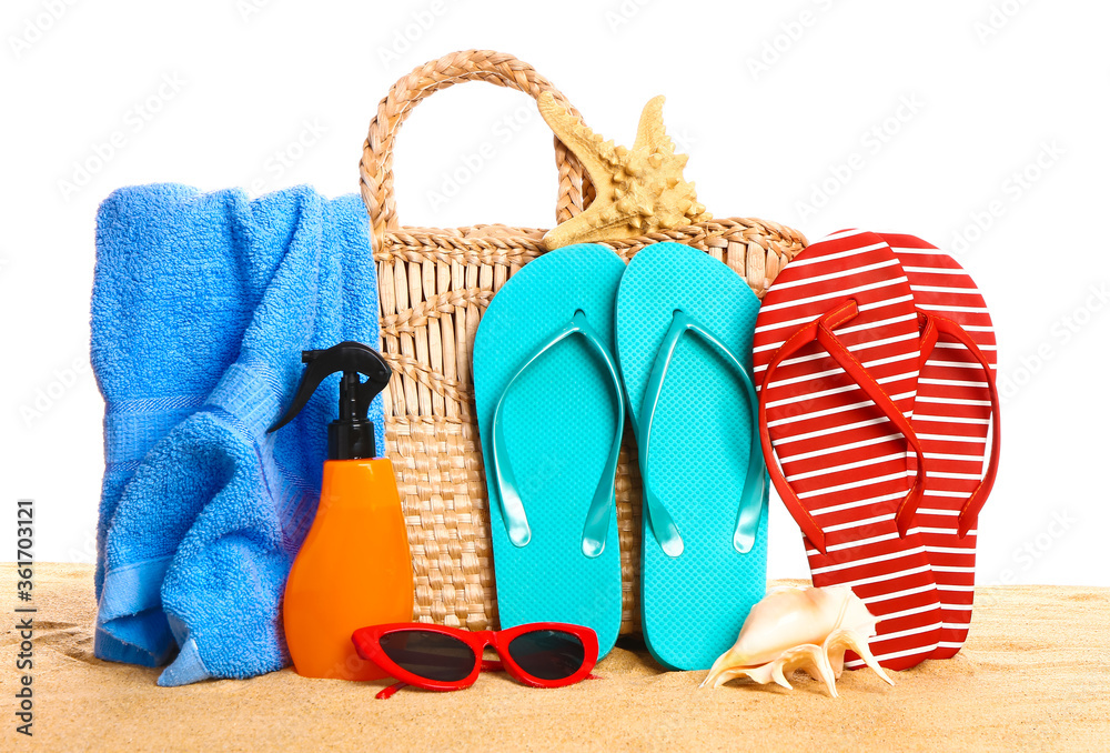 Set of beach accessories on sand against white background