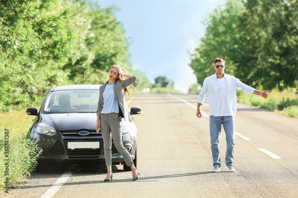 年轻夫妇在路上靠近破碎的汽车