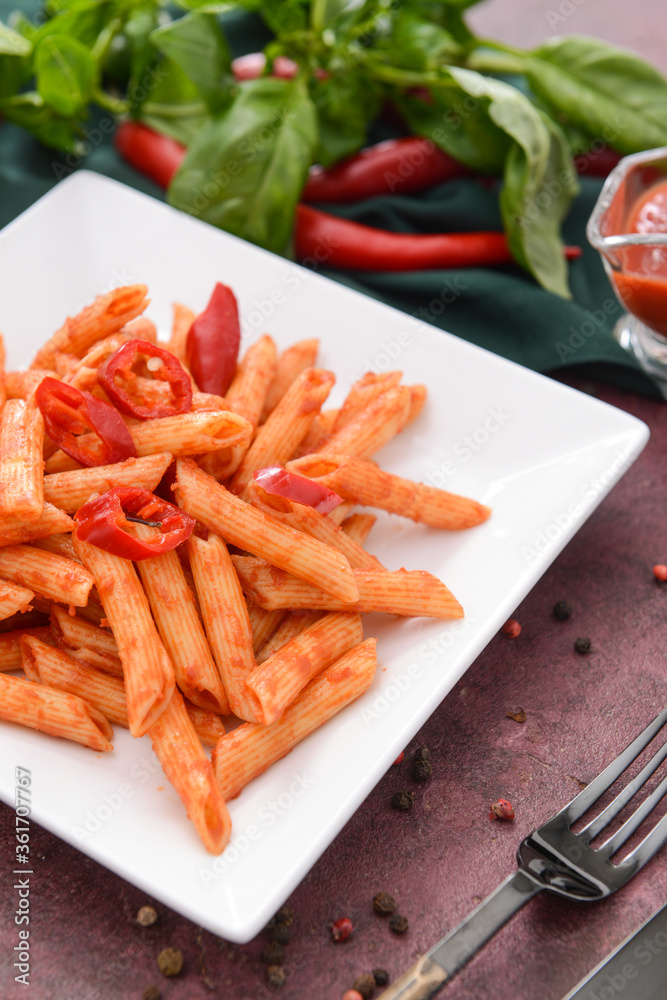 Plate with tasty pasta and tomato sauce on color background