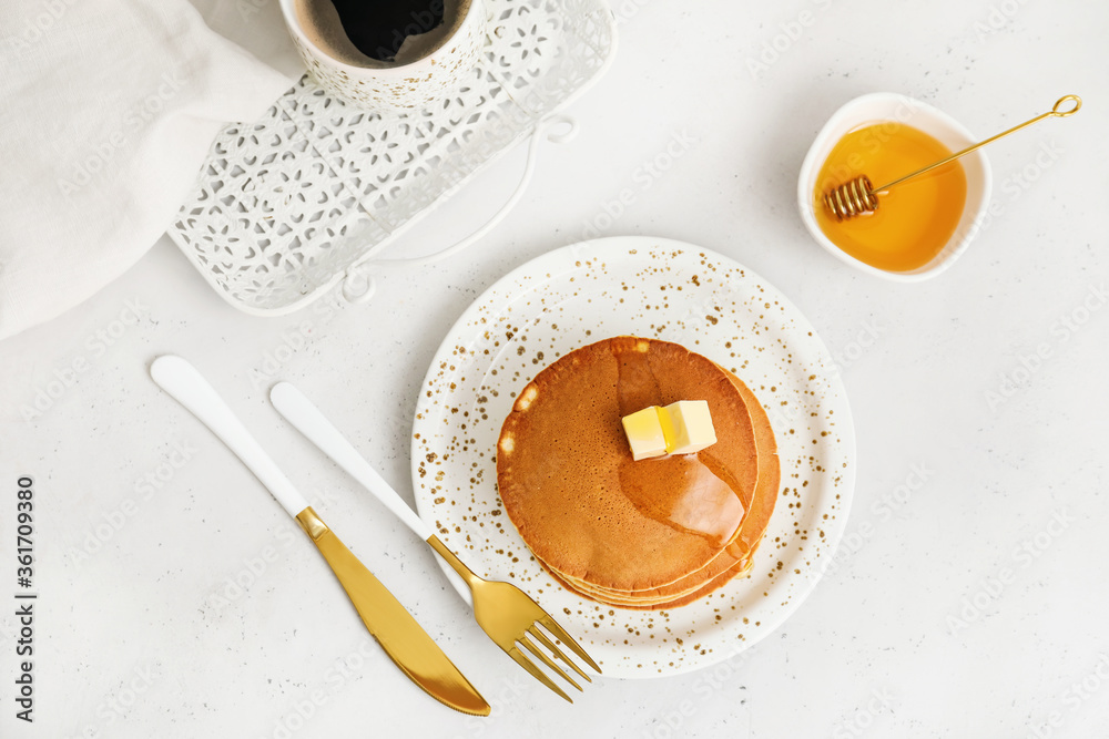 Tasty pancakes with butter, honey and cup of coffee on table