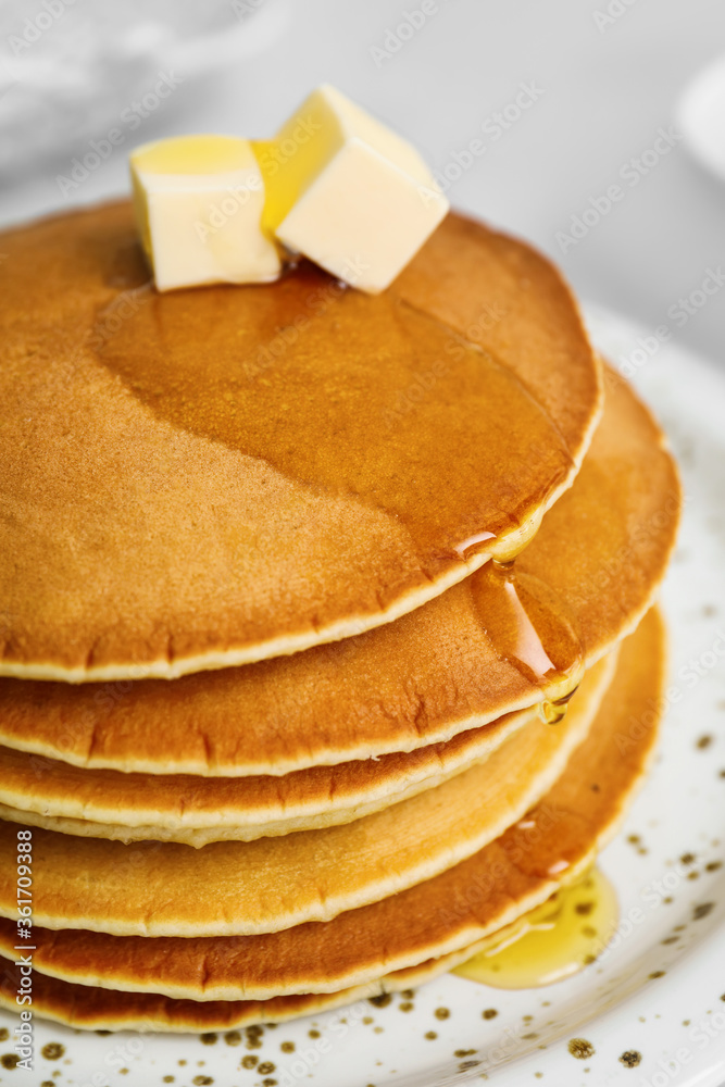 Tasty pancakes with butter and honey on plate, closeup