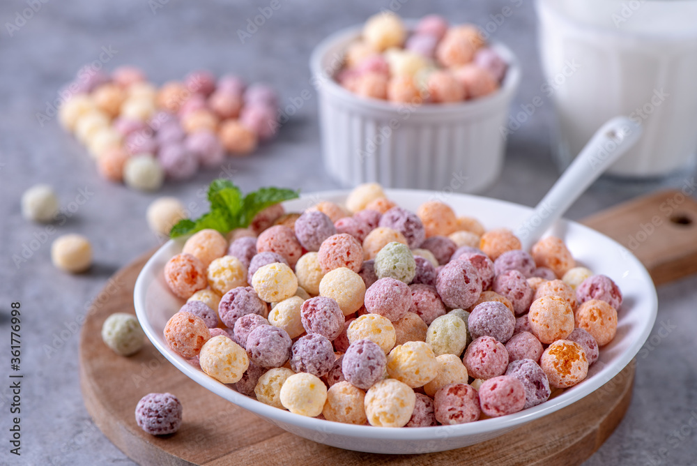 Colorful cereal corn balls mix, fruit flavor bowl sweets on gray cement background, close up, fresh,