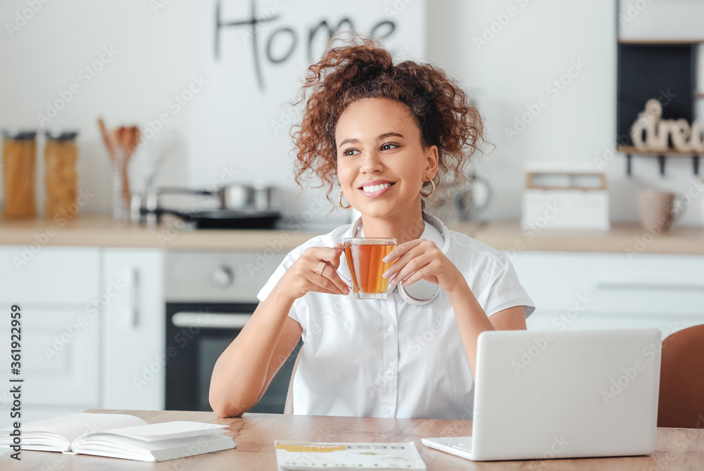 Beautiful young African-American woman drinking hot tea at home