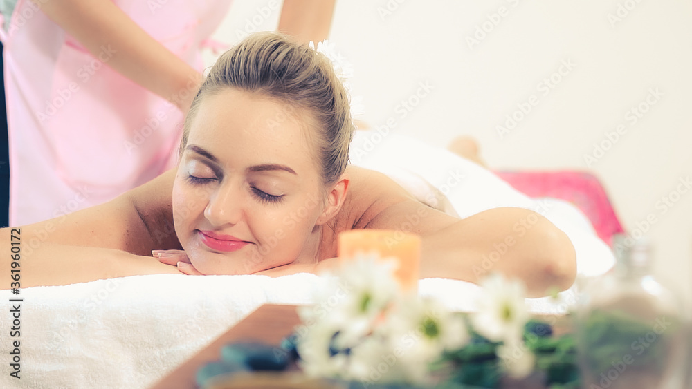 Relaxed woman getting back massage in luxury spa with professional massage therapist. Wellness, heal