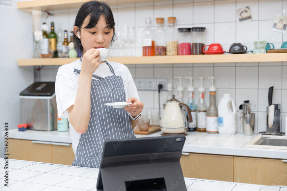 在厨房里，一边喝咖啡，一边用平板电脑，纯粹的女孩