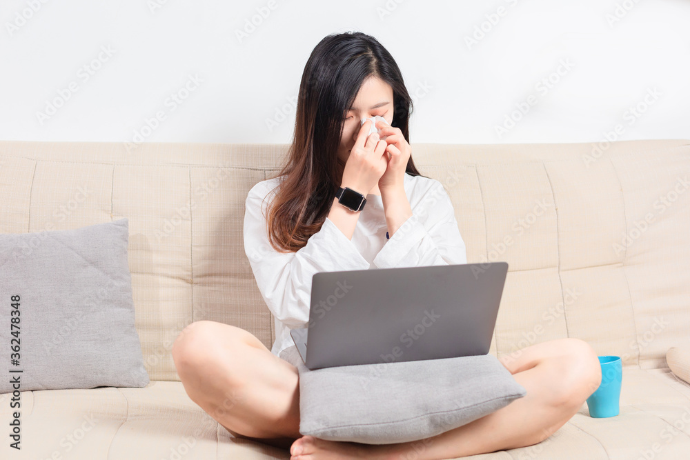 Beauty sitting on the sofa, weeping while using the computer