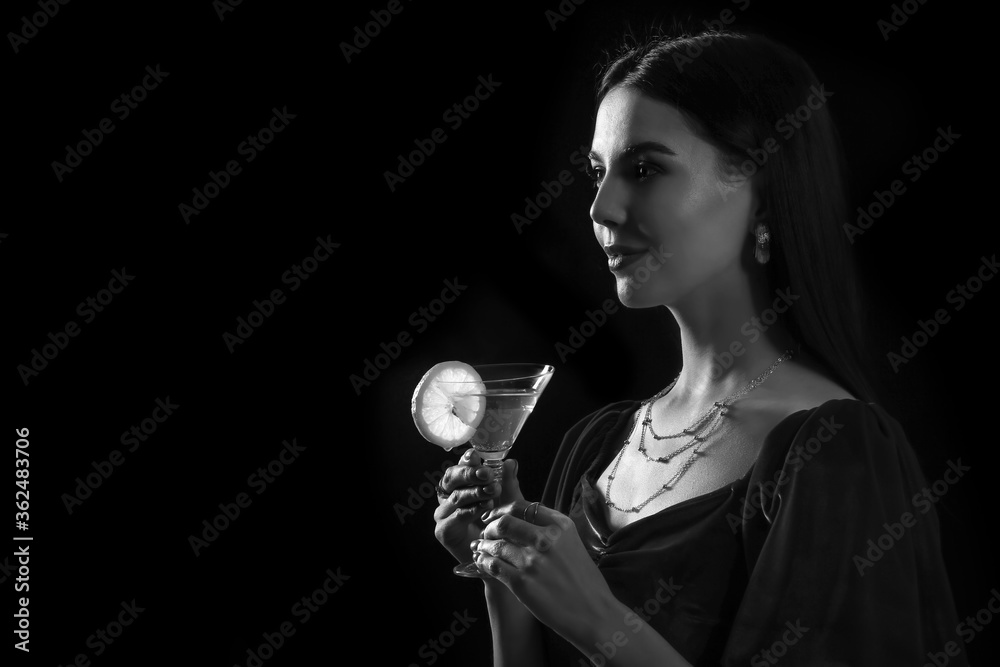 Beautiful young woman with martini on dark background