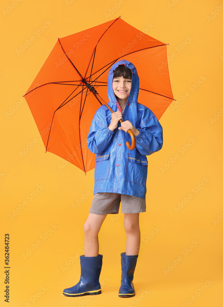 可爱的小男孩穿着雨衣，彩色背景上带着雨伞