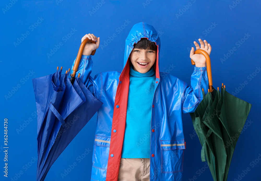 可爱的小男孩穿着雨衣，彩色背景上有雨伞