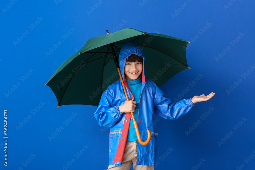 可爱的小男孩穿着雨衣，背景是雨伞