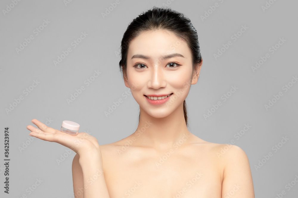 灰色背景下，手里拿着塑料瓶的亚洲美女的特写脸