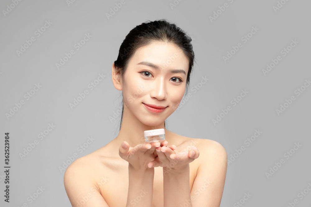 Close-up face of beautiful Asian woman holding plastic vial in hand as display in grey background
