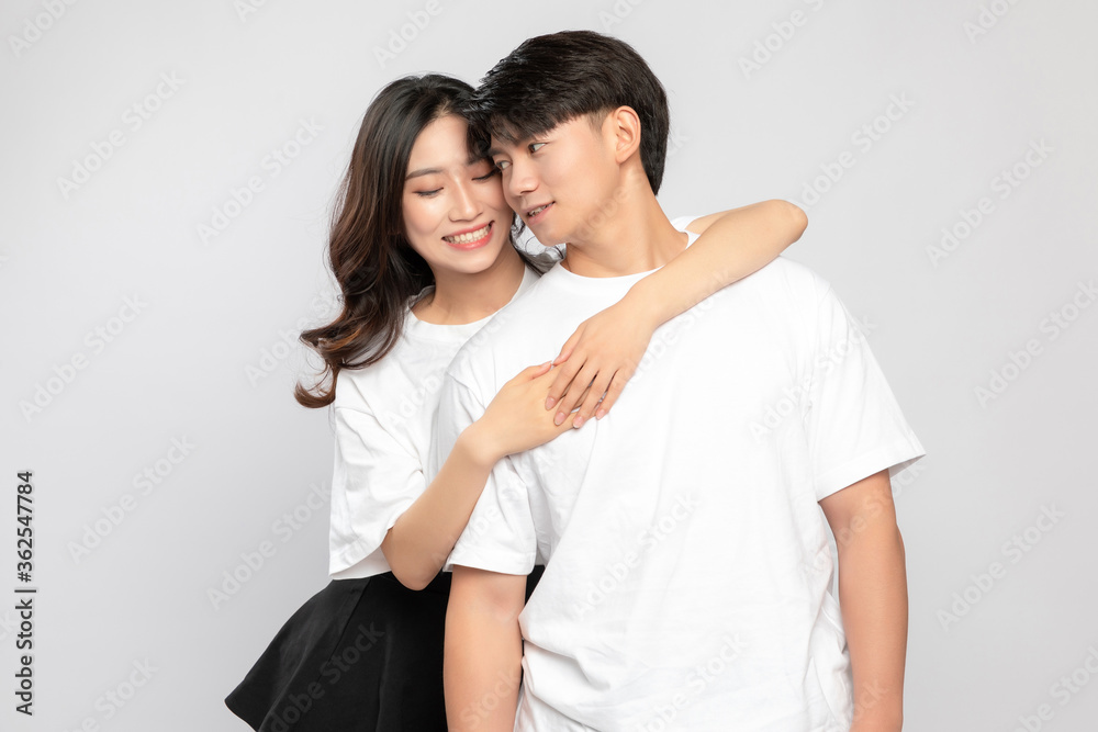 Young Asian lovers embracing in the gray background

