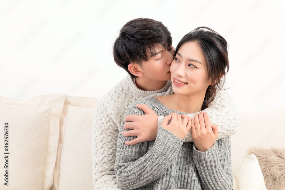 Sitting on the sofa, a pair of intimate young Asian lovers, the boy gently hugged the girl

