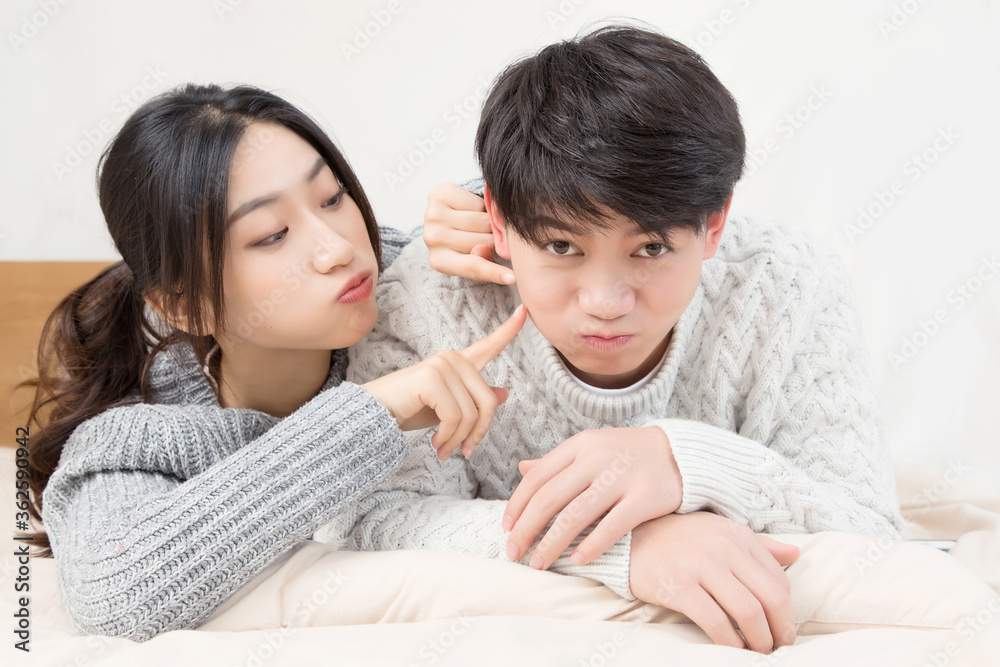 A pair of intimate young Asian lovers lying at the head of the bed

