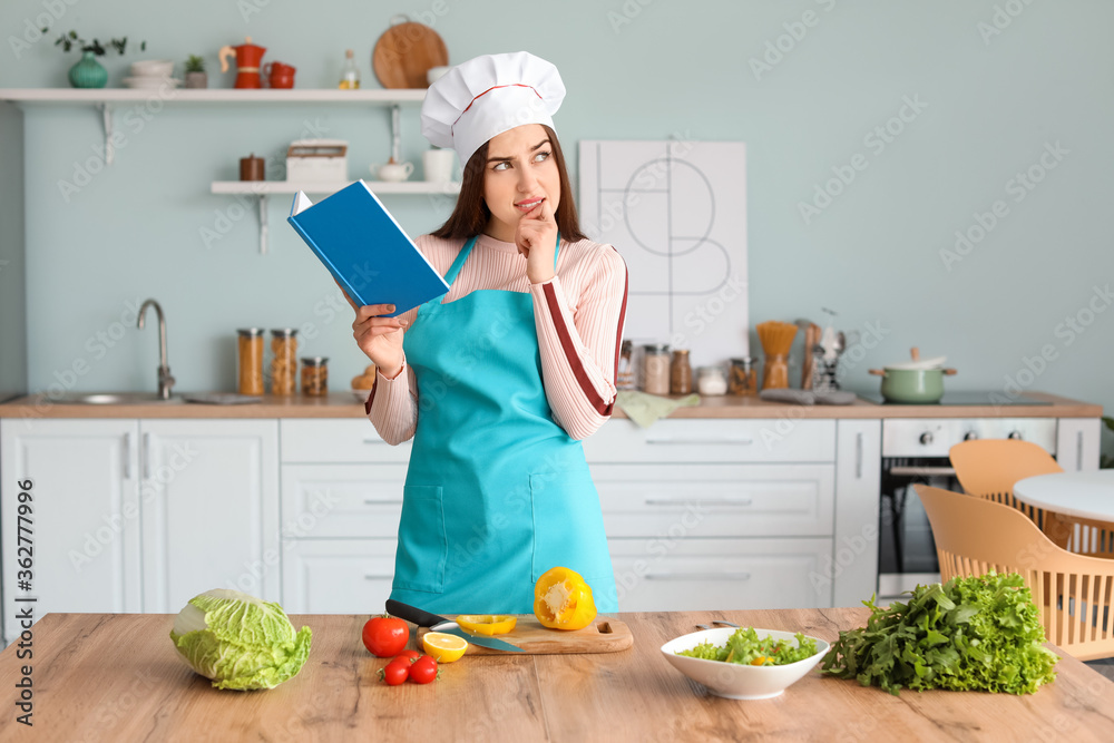 年轻女人拿着菜谱在厨房做饭