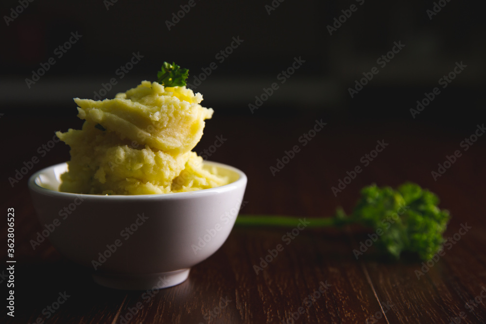 Mashed potatoes in a white bowl on a brown wooden floor