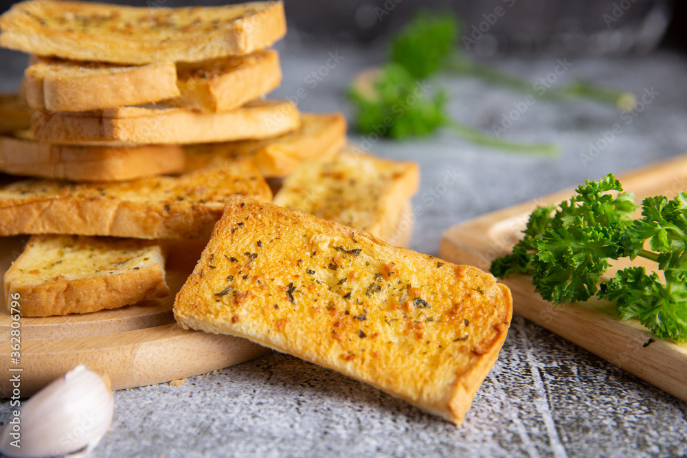 Wooden cutting board with delicious homemade garlic bread on the cement floor