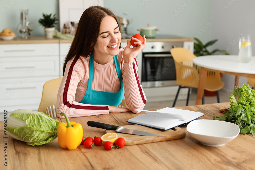 厨房里有食谱和产品的年轻女人