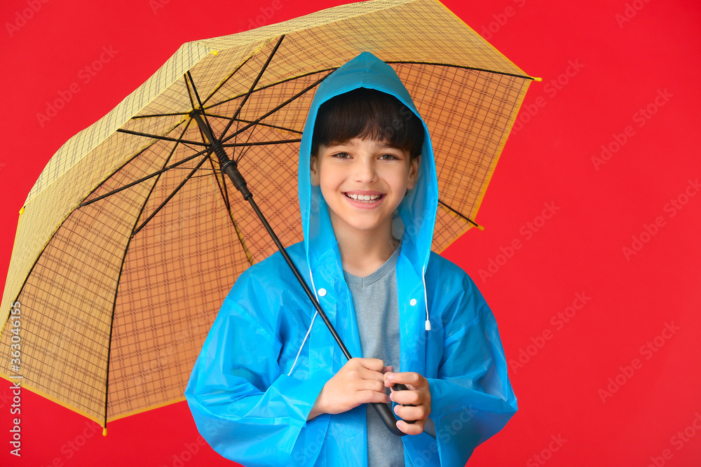 可爱的小男孩穿着雨衣，颜色背景上有雨伞