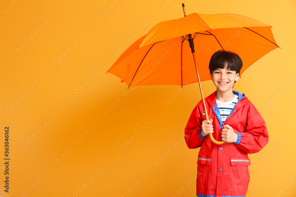 可爱的小男孩穿着雨衣，背景是雨伞