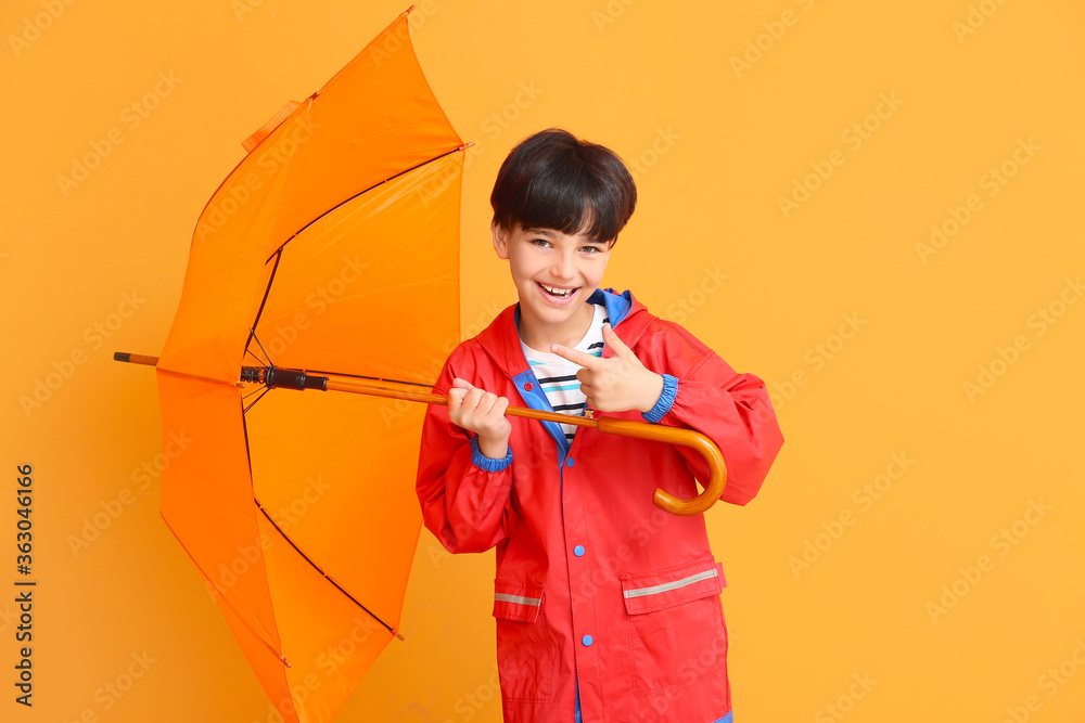 可爱的小男孩穿着雨衣，彩色背景上带着雨伞