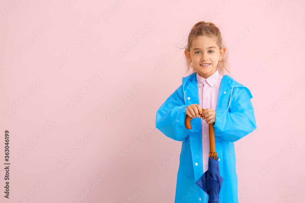 Cute little girl in raincoat on color background