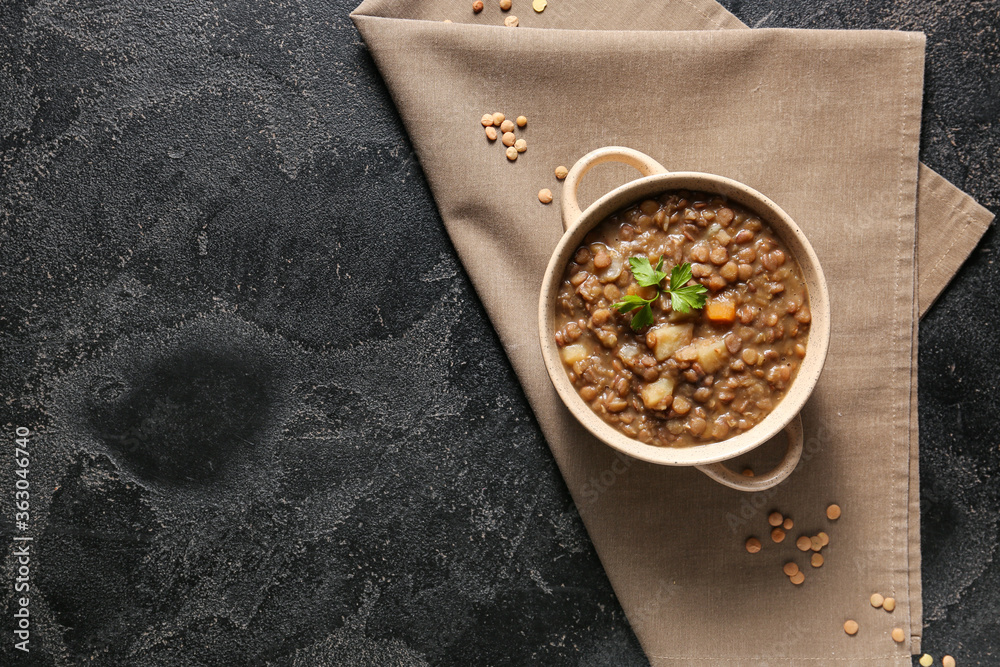 Pot of tasty lentils soup on dark background