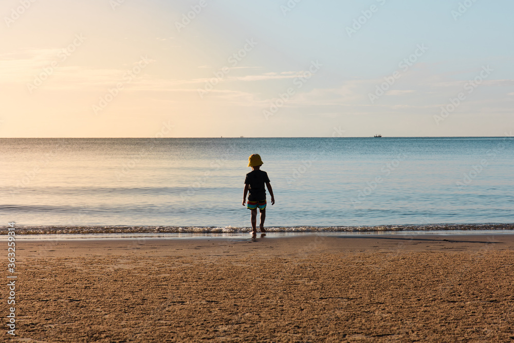 站在海滩上的男孩的侧影他看着大海