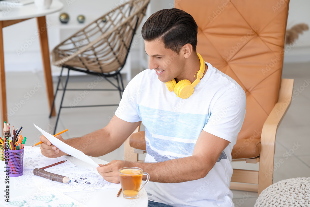 Young man coloring pictures at home