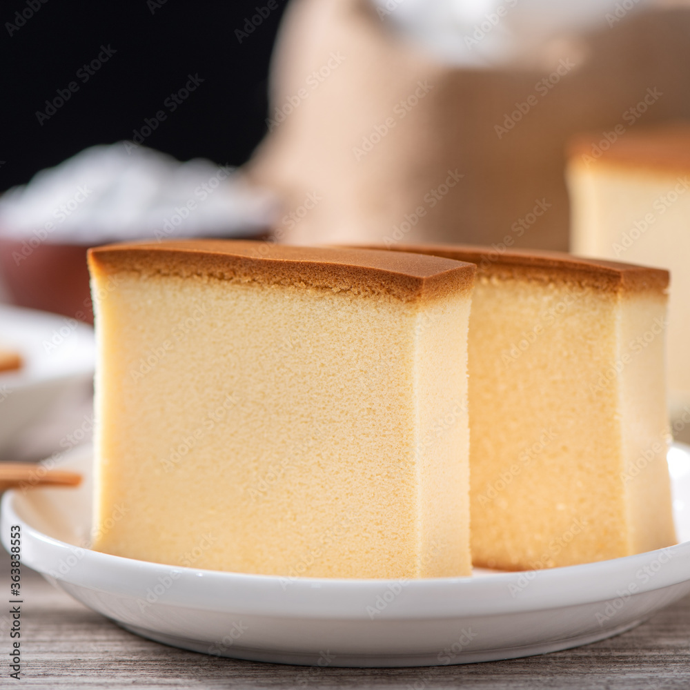 Castella（kasutera）-美味的日本切片海绵蛋糕食品，放在乡村木t上的白色盘子里