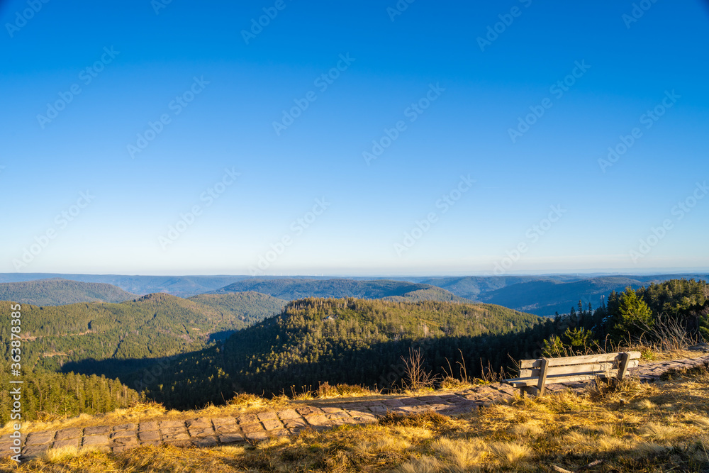 Bench at mountaintop in sunlight, looking far into the distance