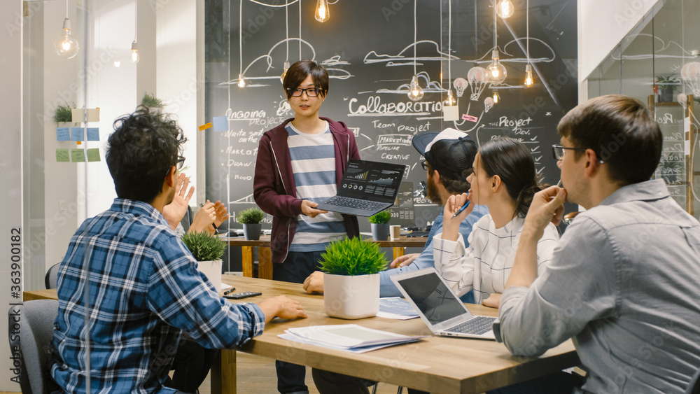 Charismatic Asian Team Leader Shows Laptop with Data Statistics to Diverse Group of Talented Young D