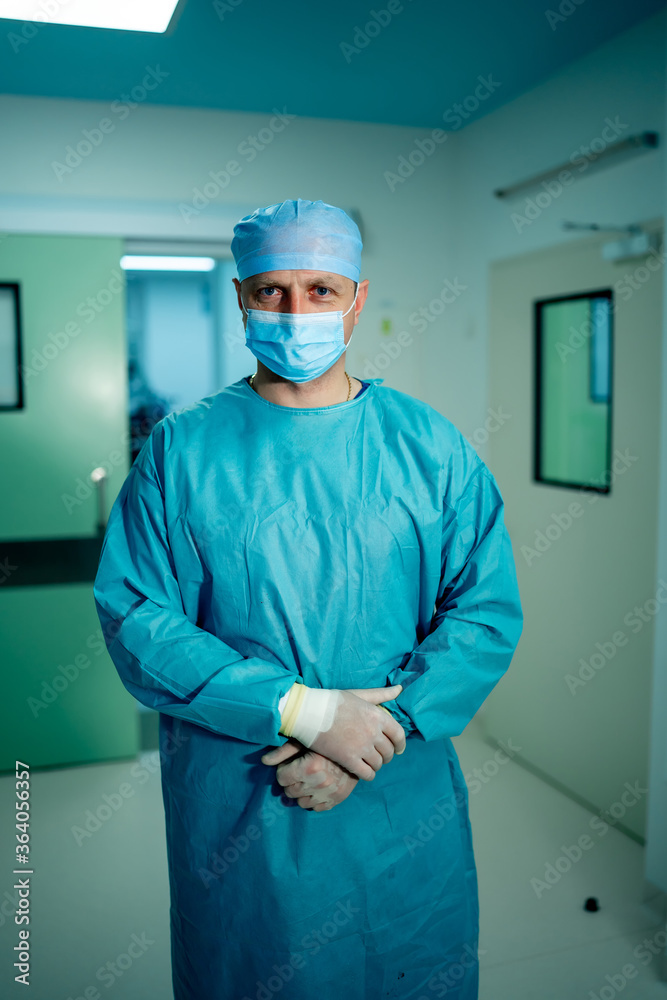 Portrait of surgeon in scrubs standing in operating theatre. Portrait of male doctor in modern medic