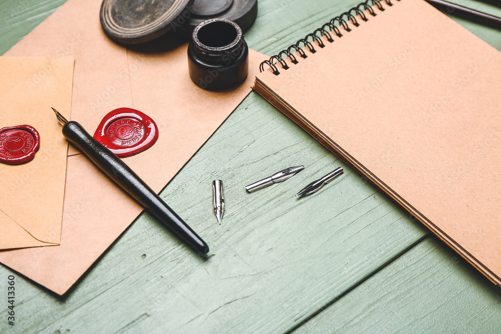 Notebook, nib pen, envelopes and ink on table