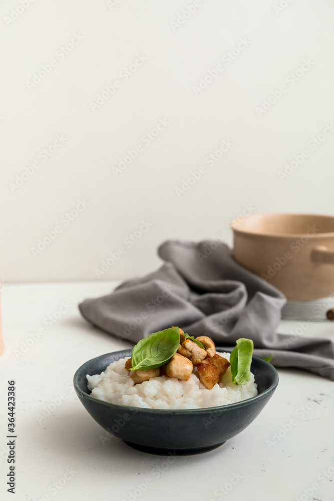 Bowl with boiled rice and chicken on table