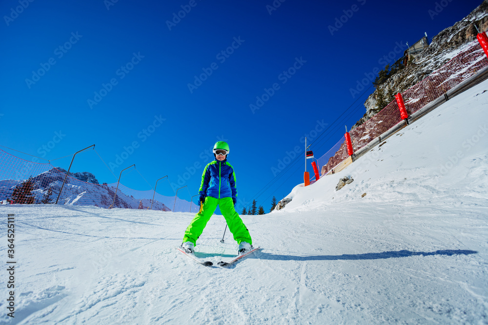 小男孩很高兴在晴朗的天气里学会如何在山路上滑雪