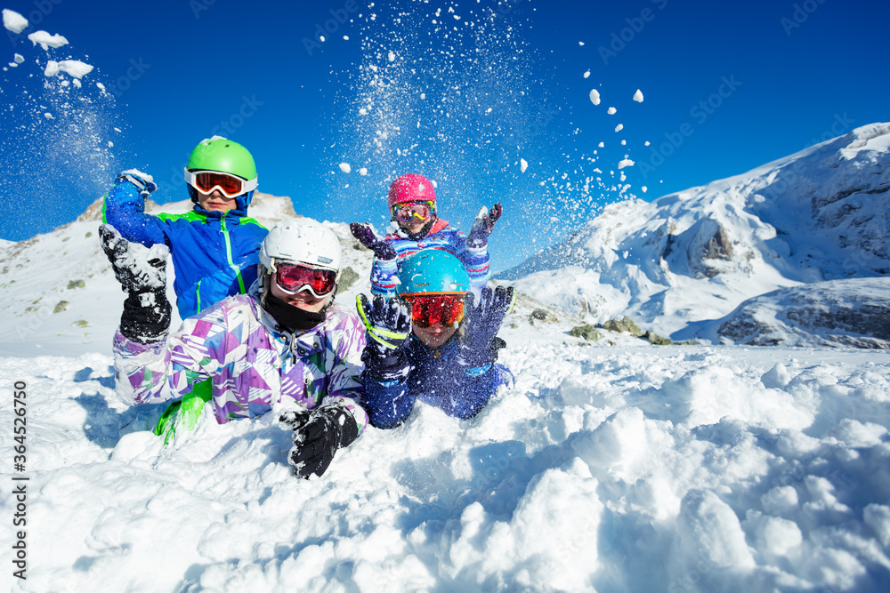 一群孩子躺在地上的画像在美丽的山上向空中扔雪