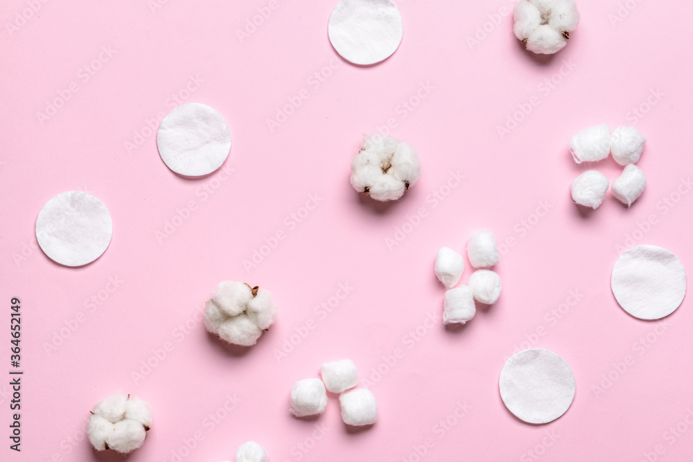 Cotton balls with pads and flowers on color background